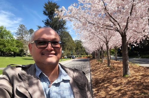 A man next to cherry blossoms